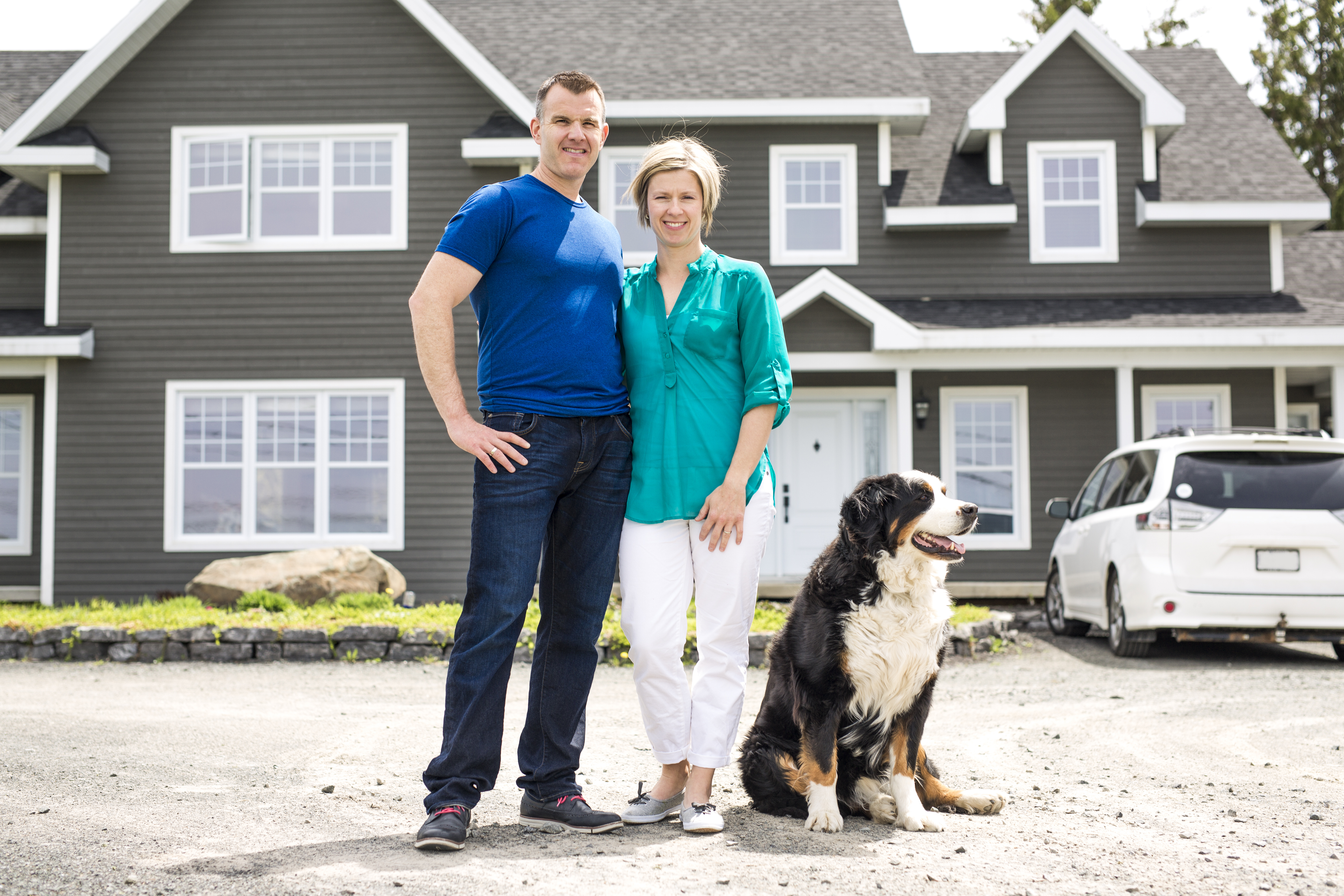 man and woman standing in front of house with dog
