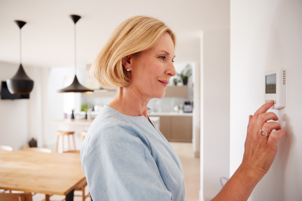 woman pushing buttons on wall thermostat